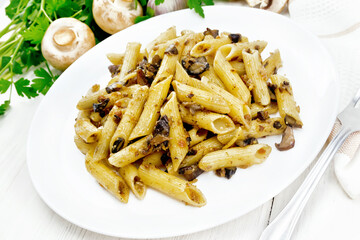 Pasta with mushrooms in white plate on light board