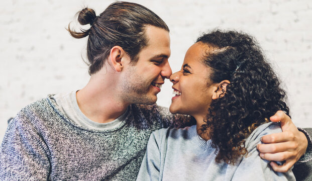 Romantic young happy love couple caucasian man and african american woman smile and have fun hugging together in valentine day on the bed at home