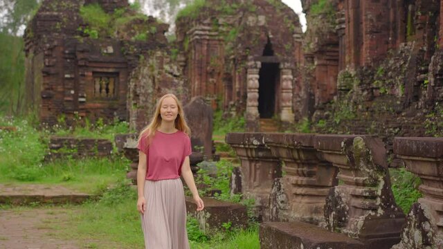 A young woman tourist is walking through ruins in the My Son Sanctuary, remains of an ancient Cham civilization in Vietnam.Tourist destination in the city of Danang. Travel to Vietnam concept