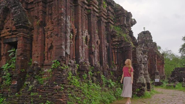 A young woman tourist is walking through ruins in the My Son Sanctuary, remains of an ancient Cham civilization in Vietnam.Tourist destination in the city of Danang. Travel to Vietnam concept