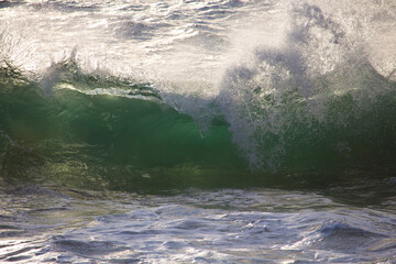 Spectacular white backwash from the  Indian Ocean waves breaking on basalt rocks at  Ocean Beach Bunbury Western Australia on a sunny morning in early winter sends salty spray high into the air.