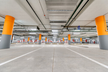 Large underground parking for cars, columns are painted red and orange.