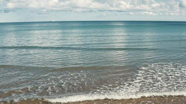 Girl is walking on the beach with ocean in the background.