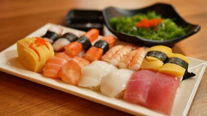 Nigiri sushi set and seaweed salad on side (Salmon, tuna, shrimp, calamari, squid, sweet egg, imitation crab)