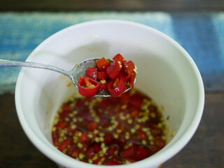 slice chili fish sauce in spoon at restaurant.