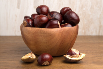 Obraz premium Buckeye Chestnut in wooden bowl on wooden surface. Side View formation of Fresh conkers.
