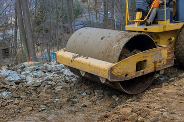 Fototapeta premium The bulldozer moves soil doing landscaping works on construction moving soil