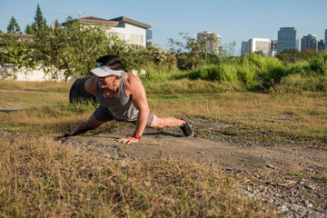 An athletic asian guy working out outdoors, doing one arm pushups on the ground. Calisthenics or...