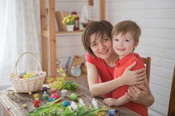 Mother and her son painting Easter eggs. Happy family preparing for Easter day