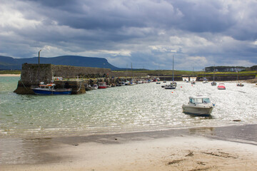 Fototapeta na wymiar Boats moored in the classic stone walled harbour in the small picturesque village of Mullaghmore in County Sligo on the West coast of Ireland