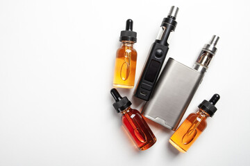 Vape juice next to smoking devices. Bottles with vape juice on a white table. Devices for vaping...