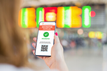 Person in airport holding mobile phone showing valid digital vaccination certificate
