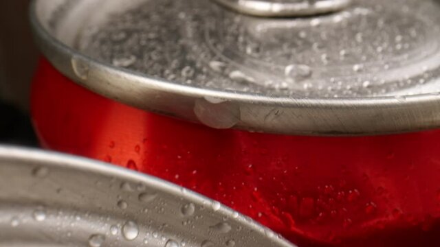 Close-up of sliding along wet cola cans.