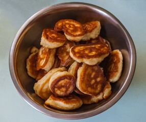 Fried dough pancakes close up in a metal dish on a blue background of the table