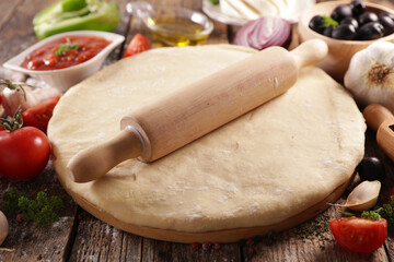 pizza dough with ingredient on wooden board