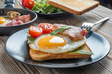 Clouse up view of fried eggs on plate and pan with fork, mushrooms and rukkola. Soft focus