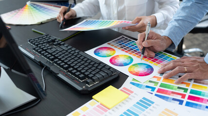 graphic designer team working on web design using color swatches editing artwork using tablet and a...