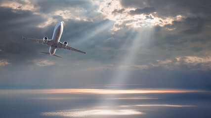 Commerical airplane flying over tropical sea at sunset
