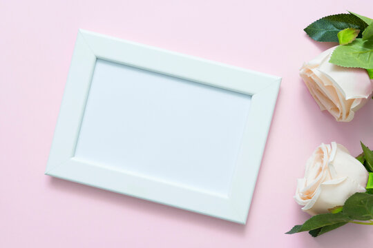 Blank white frame mockup with pastel roses on pink backgroud for love, wedding or valentine day theme.