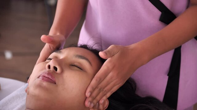 Young Asian woman getting facial massage with aroma essential oil in luxury spa salon