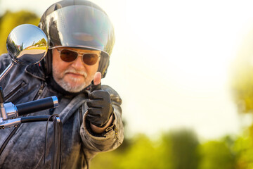Ein Motorradfahrer mit Helm und Sonnenbrille grüßt freundlich