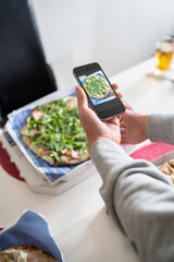 Blogger Man takes a picture with his smart phone of the pizza he is sharing with friends, for his followers on social networks.Copy space