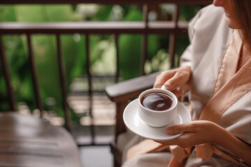 Woman holding cup of hot steaming drink tea on the  balcony with tropical view