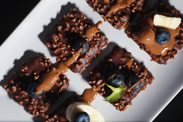 Chocolate dessert with nuts and fresh berries. Sweet snack for coffee biscuit in glaze and nut crumbs with fruit.