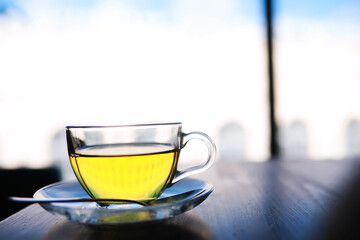 Hot steaming green tea in a cup on a rustic background