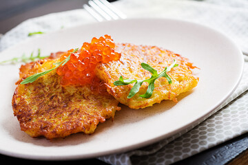 Fried potato pancakes with red caviar and sour cream, fritter, roesti. Traditional delicious food, lunch.