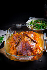 Homemade baked duck. Crispy whole roast duck. Thanksgiving or Christmas dinner. Roast duck with thyme and pumpkin on rustic wooden table.