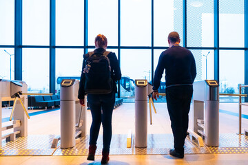 Turnstiles in the building. People pass through the turnstiles. Control over the direction of movement of people. Turnstiles with turntables. Security system in the building. Pass system.