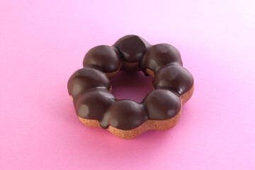 ピンクの背景に置かれた,甘いチョコレートドーナツ