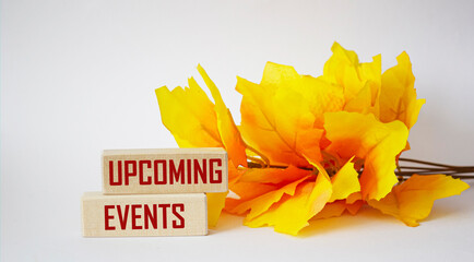 Upcoming events concept, office desk with orange branch. Upcoming events text written on wooden blocks.