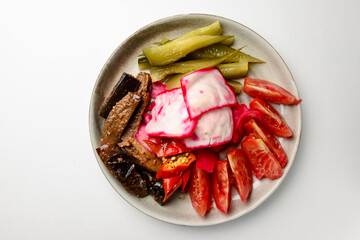 Preserved vegetables cut and served on a white plate. Pickled cucumbers, tomatoes, cabbage.