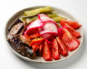 Preserved vegetables cut and served on a white plate. Pickled cucumbers, tomatoes, cabbage.