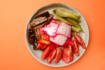 Preserved vegetables cut and served on a white plate. Pickled cucumbers, tomatoes, cabbage.