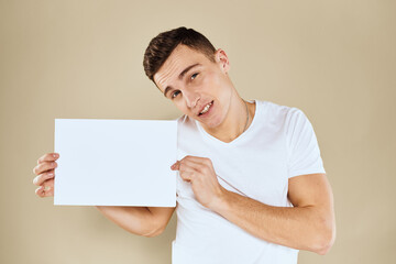 man in white t-shirt sheet of paper in hands Copy Space cropped view beige background