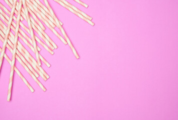 Flat lay with striped drink straws on pink background