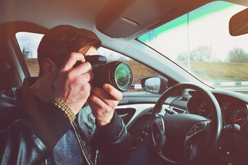 A man is taking pictures from a car window. Photographer traveler. The work of a private detective