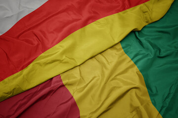 waving colorful flag of guinea and national flag of south ossetia.