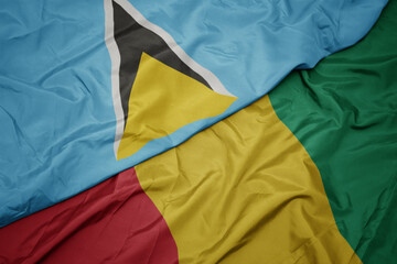 waving colorful flag of guinea and national flag of saint lucia.