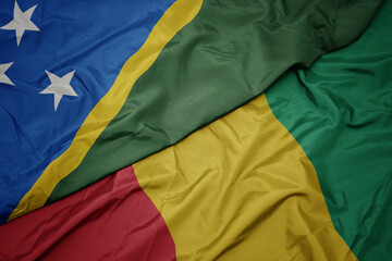 waving colorful flag of guinea and national flag of Solomon Islands .