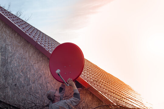 man installs a satellite TV dish on the roof of the house. Independent TV communication in a private home