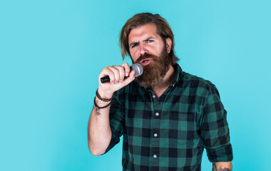 guy with beard singing in microphone. confidence and charisma on stage. bearded man wearing...