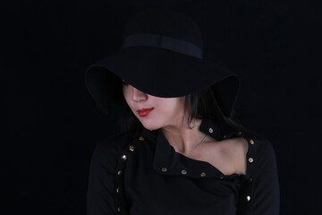 close-up studio portrait of a beautiful girl in a black hat on a black background