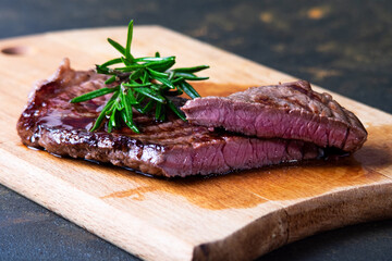 black angus steak with tomatoes, rosemary and lettuce on a board