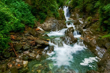 Naklejka na ściany i meble green clear water in a mountain brook with waterfalls