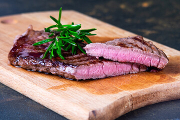 black angus steak with tomatoes, rosemary and lettuce on a board