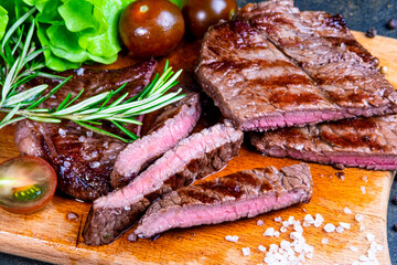 black angus steak with tomatoes, rosemary and lettuce on a board